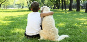 a boy and dog sitting in grass